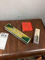 Three boxed harmonicas of various sizes on a wooden surface