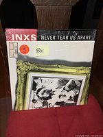 Front cover of the INXS Never Tear Us Apart vinyl LP album showing the photo frame design and band name.