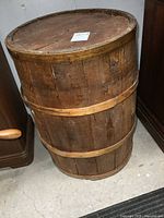 Full view of a vintage wooden barrel showing its cylindrical shape and wooden rings securing the planks.