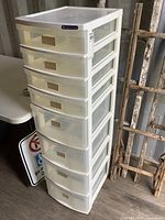 Tall white translucent plastic organizer with 8 drawers from a side angle with some background items.
