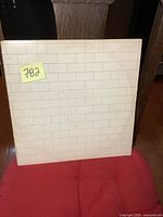Front cover of Pink Floyd The Wall double LP showing white brick wall design with slight wear marks and a lot number sticky note
