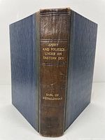 Front view showing spine with title and author name embossed in gold on brown leather with dark blue boards.
