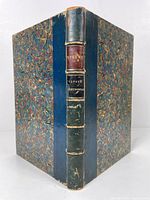 Front view showing blue leather spine with colored labels for 'Sterne' and 'Voyage Sentimental'. Marbled paper covers with rubbing and some wear.