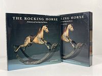 Front cover of the book with dust jacket and slipcase, showing a painted wooden rocking horse sculpture.