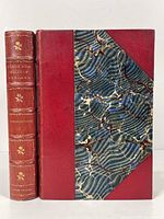 Front view of one volume showing the marbled cover and red leather binding with gold embossed spine text and floral designs.