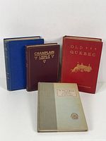 Four vintage books standing arranged with spines showing titles and condition.