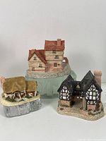 Front and side view of the three collectible cottages by David Winter, showing different architectural designs and detailed painting.