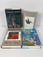 Four Timothy Findley hardcover books standing and lying flat, showing front covers with original dust jackets. Titles visible are Pilgrim, Headhunter, The Telling of Lies, and The Stillborn Lover. Books appear in good condition and include the author's signature.