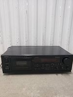 Front view of Denon DRM-650s cassette deck showing cassette compartment, control buttons, knobs, and display.