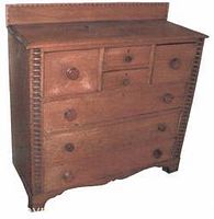 Front angle view of antique 19th century beechwood bonnet chest showing drawers, knobs, and backsplash detail.