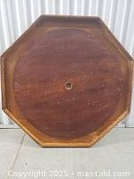 Top view of the antique, octagonal crokinole board showing wood surface and exposed screws on posts.