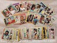 Mixed collection of approximately 120 football cards from the 1970s spread out on display, showing front faces with player portraits and some team logos visible.