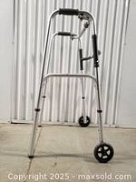 Front view of the aluminum walker showing structure, handles with rubber grips, and two small front wheels.