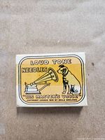 Yellow His Master's Voice Loud Tone Needles box with logo of gramophone and dog and visible scratches.