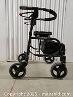 Side view of black Nexus rollator showing foldable frame, four wheels, handle grips with brakes, basket under padded seat.