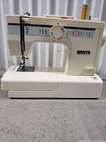 Side view of white colored White brand sewing machine model 1855 showing stitch selection dial and sewing platform.