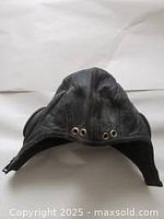 Front top view of black leather aviator hat showing ventilation grommets and overall shape.