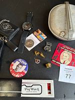 Group shot showing all items including mess kit, wristwatch, wallet, pins, coin, patch, button, Pen Watch manual
