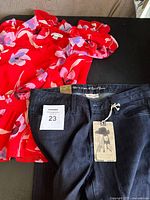Jeans with tags and floral blouse side by side