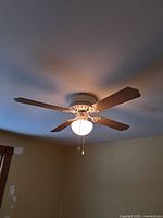 Ceiling fan mounted, light on, showing oak side of blades