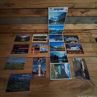 Full set of postcards laid out on wood surface showing 14 pieces including two tall fold-outs