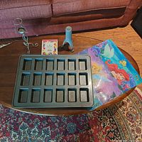 Overview of all items on coffee table: mini loaf pan, pot stirrer, candleholder, placemat, recipe cards