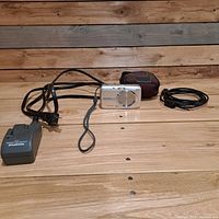 Camera, charger with AC cord, USB/AV cable, and case laid out