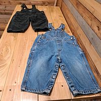 Both pairs of toddler overalls laid flat on table