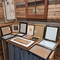 Group shot of all frames on a table and wall, showing variety of sizes and finishes