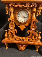 Close-up lower section with dial, floral scrollwork and base details