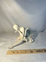 Front view of seated ballerina figurine with ruler showing size