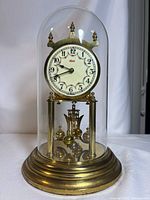 Front view of brass anniversary clock under glass dome