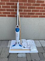 Full view of steam mop upright with measuring stick and extra pads