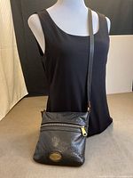 Full view of Fossil black leather crossbody purse on mannequin showing size and strap