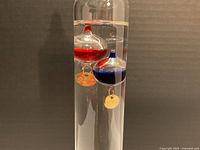 Close-up of red and blue floats with brass tags inside the glass cylinder