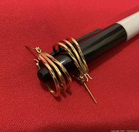 Earrings on red fabric, angled view showing triple-wire construction and hinge posts