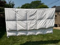 Front view of white quilted queen duvet hanging outdoors