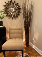Full view of branch arrangement in metal vase beside chair and mirror