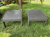 Two matching faux wicker stools on grass, front view