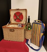 open picnic basket showing interior plates, bowls, cutlery, napkins, lighted bottle and cooler bag