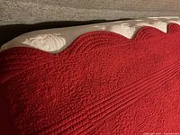 close-up of quilted stitching and scalloped edge on red coverlet