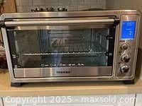 Front view showing Toshiba toaster oven powered on with digital display