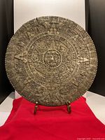 Front view of full Aztec calendar plaque on red cloth
