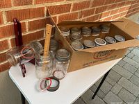 Box and table displaying multiple vintage Crown preserve jars with lids and gaskets