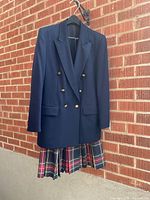 Front view of navy blazer over plaid skirt on hanger