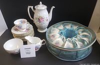 Group view of entire Aynsley tea set showing pot, creamer, sugar bowl, stack of saucers and cups in keeper
