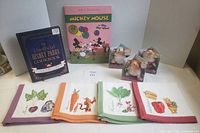Group shot of all items: two books, three boxed dwarf plush toys, four Pooh napkins
