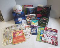 Group shot of all Pokémon items: cards, deck holder, tins, books, toys