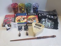 All items grouped: books, glasses, shirts, figurine, keychains, Trivial Pursuit game, wand