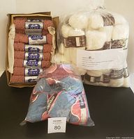 Overview of three groups of yarn in plastic bags and box